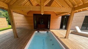 Un jacuzzi bajo una pérgola de madera con vistas a un edificio moderno.