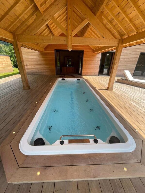 Un jacuzzi bajo una pérgola de madera con vistas a un edificio moderno.