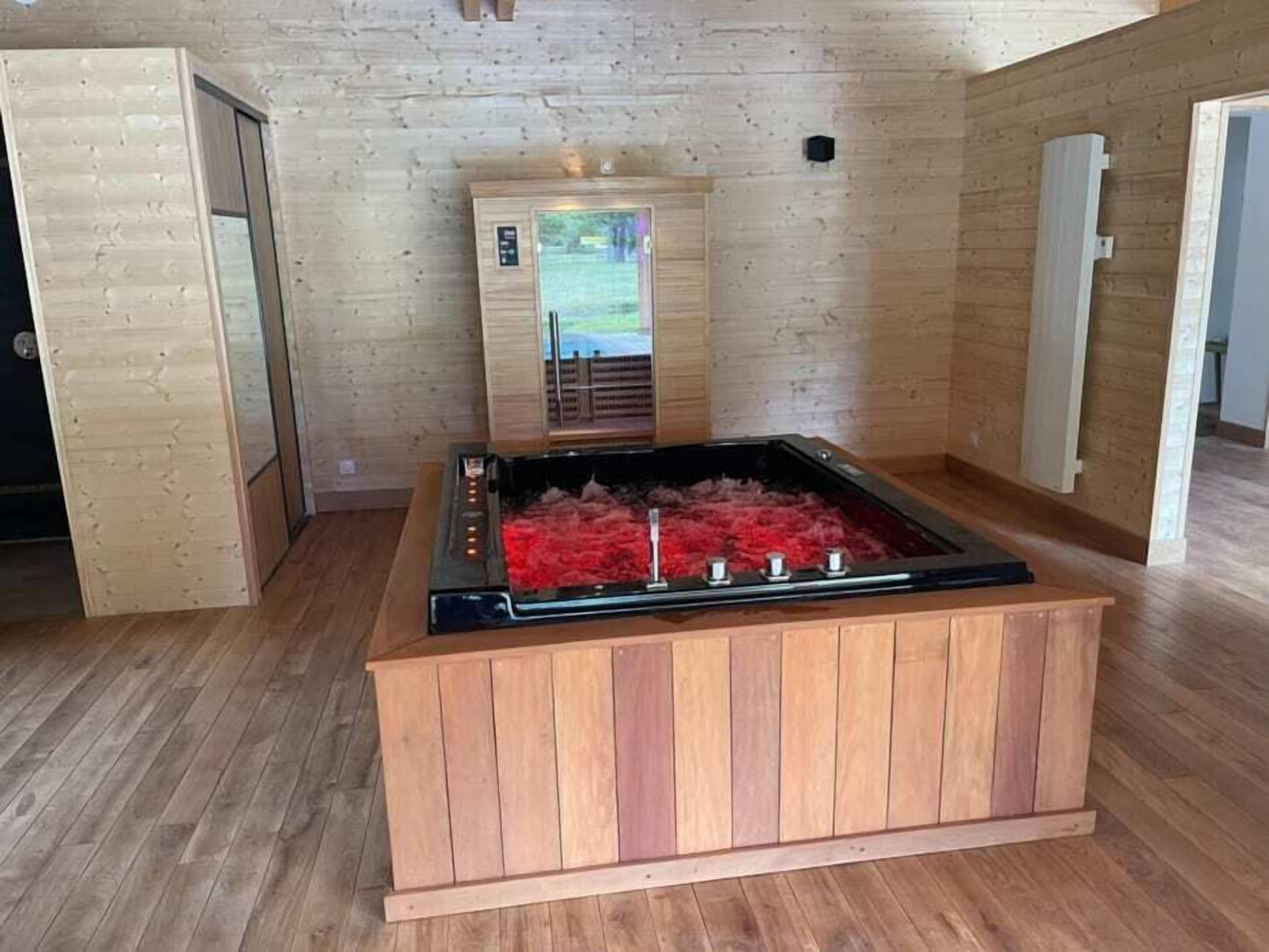 Una sauna con banco de madera y cerramiento de vidrio, ubicada en una habitación con paredes y suelos de madera.