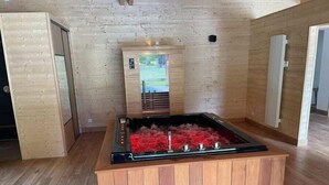 A sauna with a wooden bench and a glass enclosure, set in a room with wooden walls and floors. - Etangs de la Palombière (Montreuil-sur-Epte)