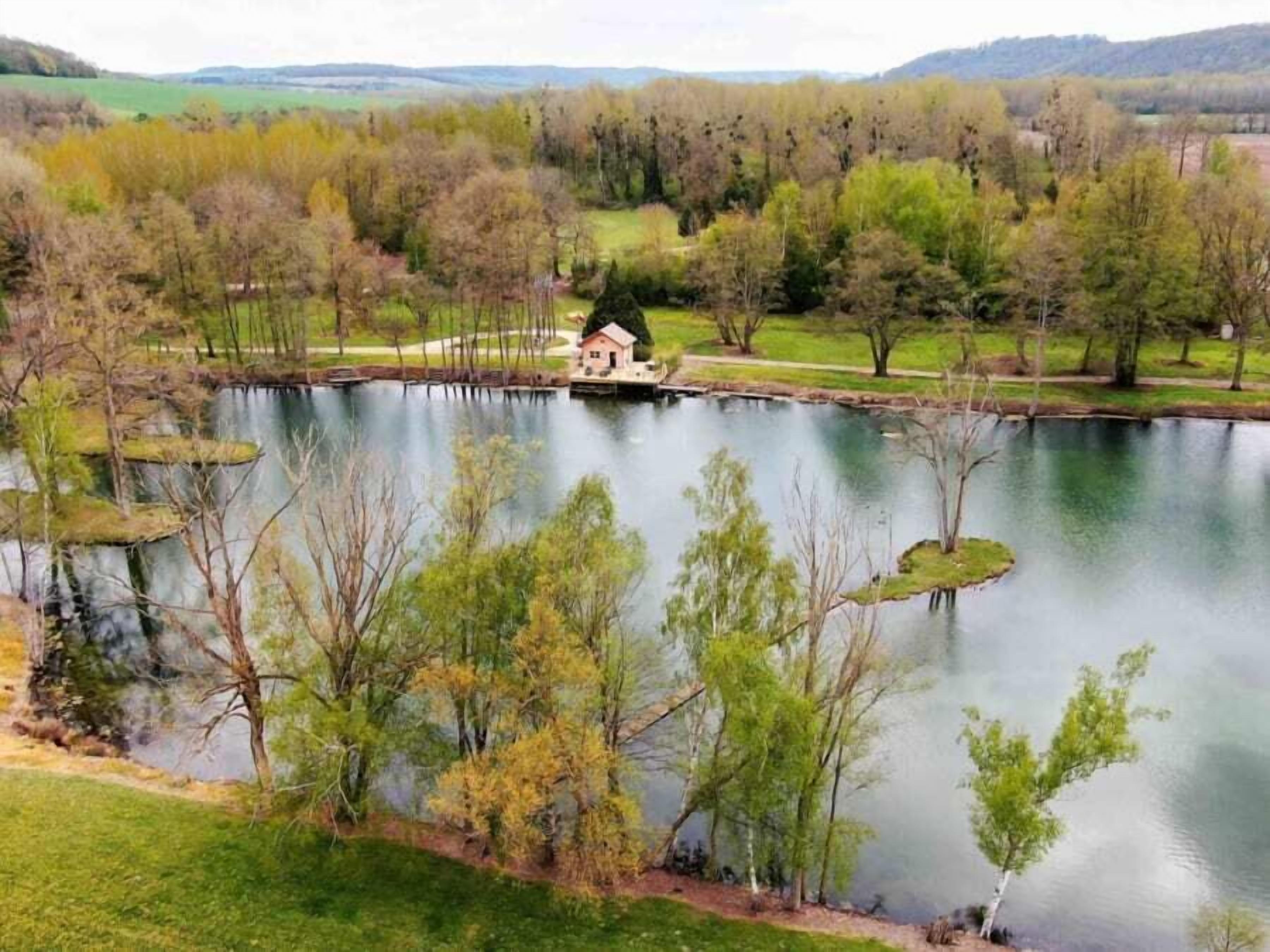 A lakeside property with a small house, surrounded by trees and a calm lake.