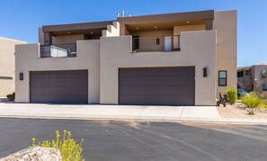 A modern two-story house with two garage doors, a balcony, and a small garden area. - Grand Coral Estate 6 Bedroom Townhouse (Washington)