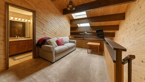 A cozy cabin interior with a wooden ceiling, a sofa with cushions, a small table, and a built-in desk with a laptop. - 254 Bldg D 2 Bedroom Townhouse (Truckee)