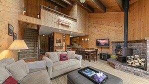 A cozy cabin interior with a fireplace, wooden walls, a dining area, and a sofa. - 254 Bldg D 2 Bedroom Townhouse (Truckee)
