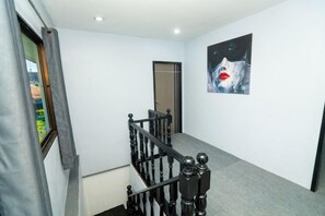 Una escalera con barandilla, una puerta en la parte superior y un cuadro en la pared.