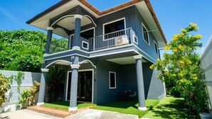 A two-story house with a balcony, a covered porch, and a well-maintained lawn.