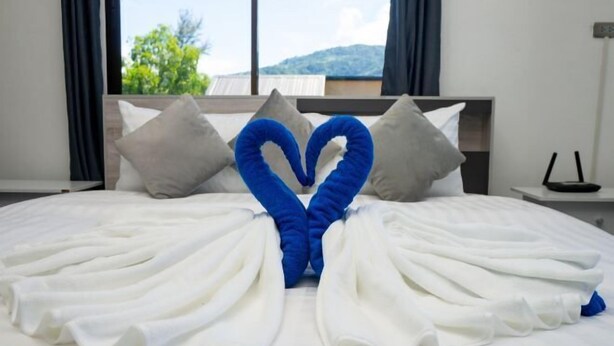 A hotel room with a bed, pillows, and a view of the outdoors.