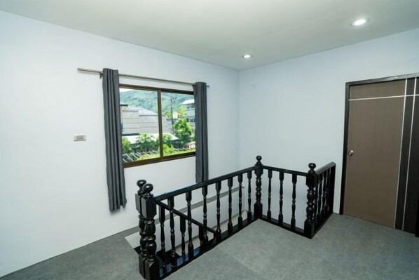 Una habitación con ventana, puerta y escalera.