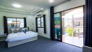 A modern hotel room with a large bed, a balcony with a view, and a sliding glass door.