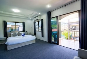 Ein modernes Hotelzimmer mit einem großen Bett, einem Balkon mit Blick und einer Schiebeglastür.