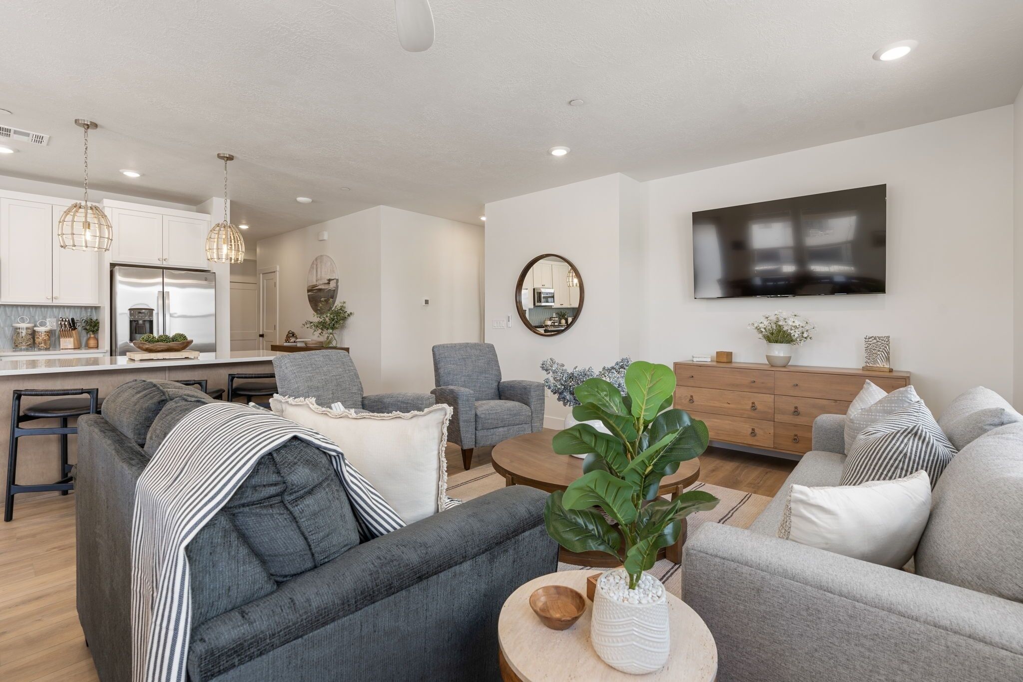 A modern living room with grey sofas, a coffee table, and a TV mounted on the wall.