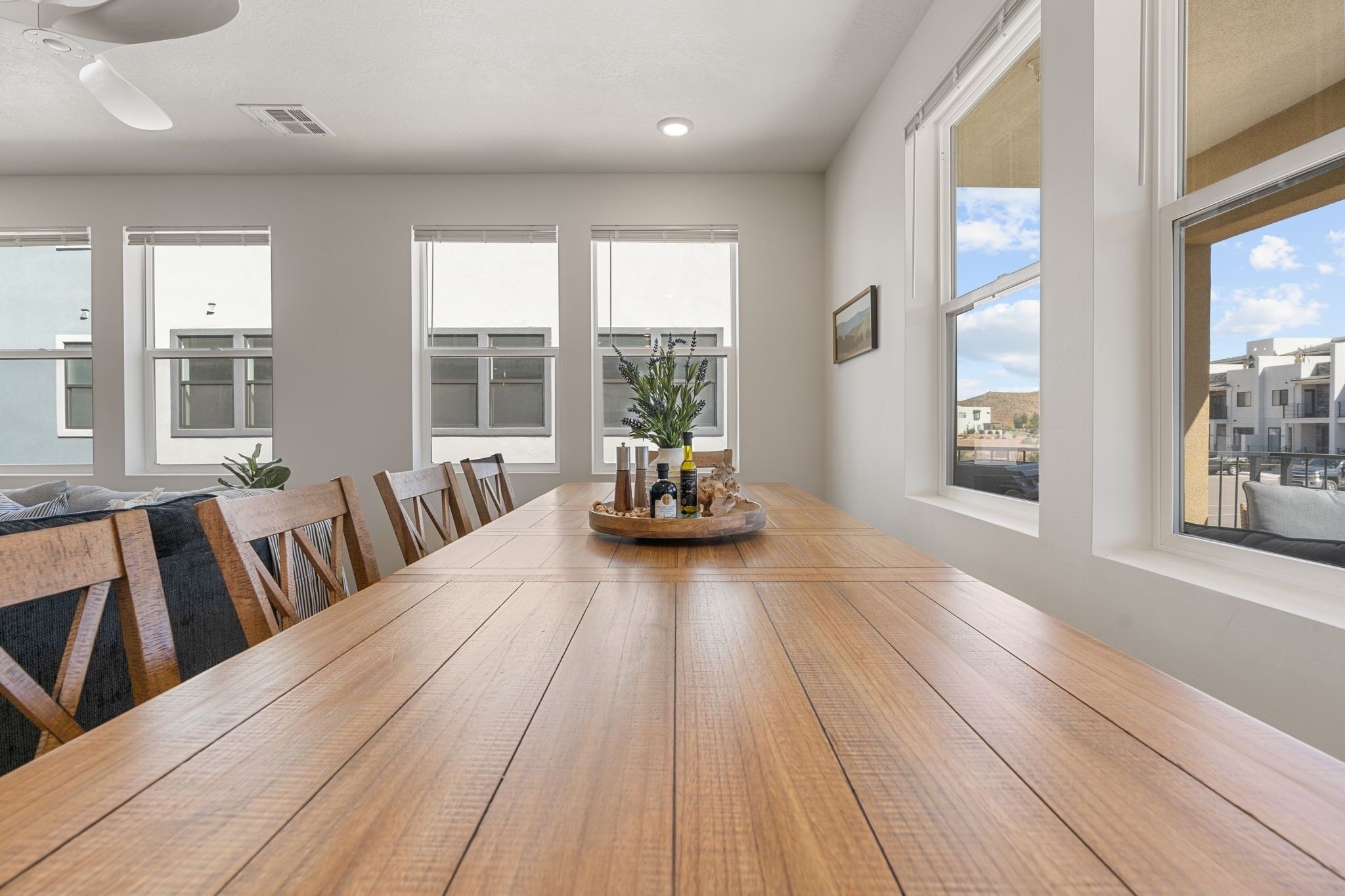 A spacious dining area with a long wooden table, multiple chairs, and a central decorative piece.