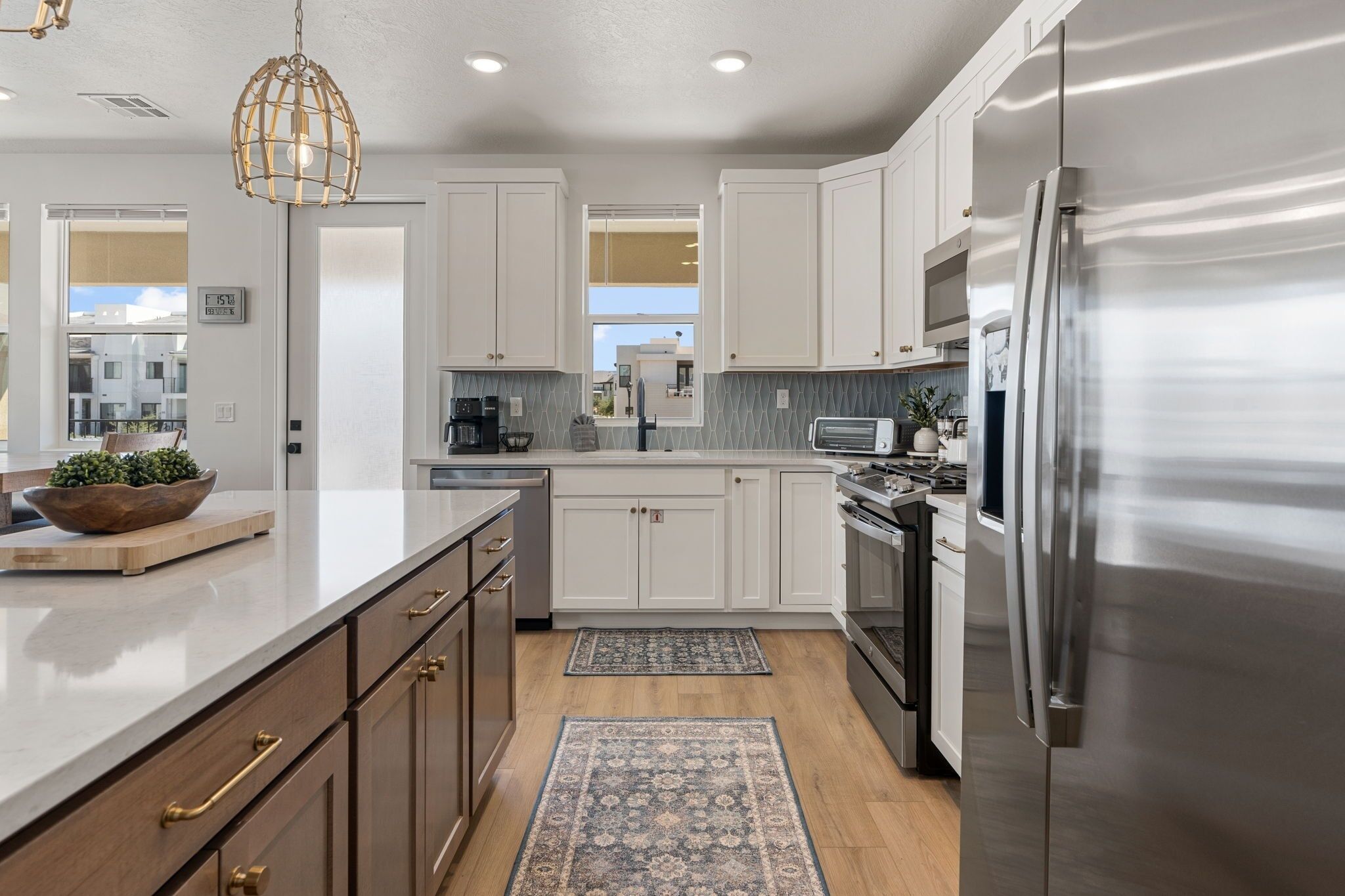 A modern kitchen with white cabinets, stainless steel appliances, and a wooden island.