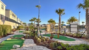 A golf course with a clear path, palm trees, and a building in the background. - Stunning 4 Bed Townhome With Splash Pool-1160ks 4 Bedroom Townhouse (Davenport)