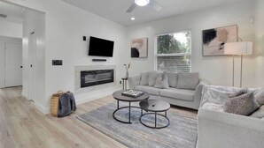 A modern living room with a fireplace, a sofa, a coffee table, and a television. - Haven Hideway Atlanta Downtown (Atlanta)