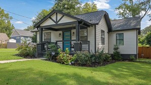 A single-story house with a front porch, a blue door, and a small garden area with flowers and shrubs. - Haven Hideway Atlanta Downtown (Atlanta)