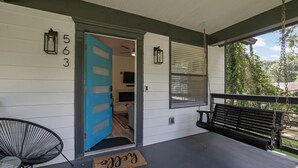 A porch with a blue door, a black swing, and a doormat. - Haven Hideway Atlanta Downtown (Atlanta)