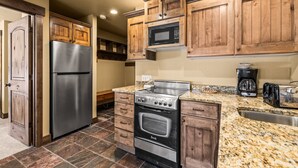Eine Küche mit Holzschränken, einem Edelstahl-Kühlschrank, einem Backofen, einer Mikrowelle und Granit Arbeitsplatten.