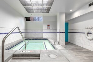 Zona de piscina con un cartel de profundidad de 9 metros, un cartel de emergencia 911 y una puerta azul.
