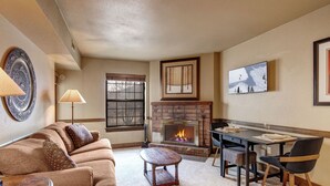 Una sala de estar con chimenea, un sofá, una mesa de centro y un comedor con sillas y una mesa.
