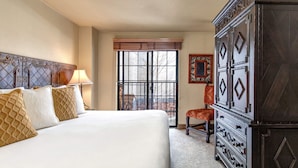 Habitación de hotel con una cama grande, un aparador y una ventana con vistas al exterior.