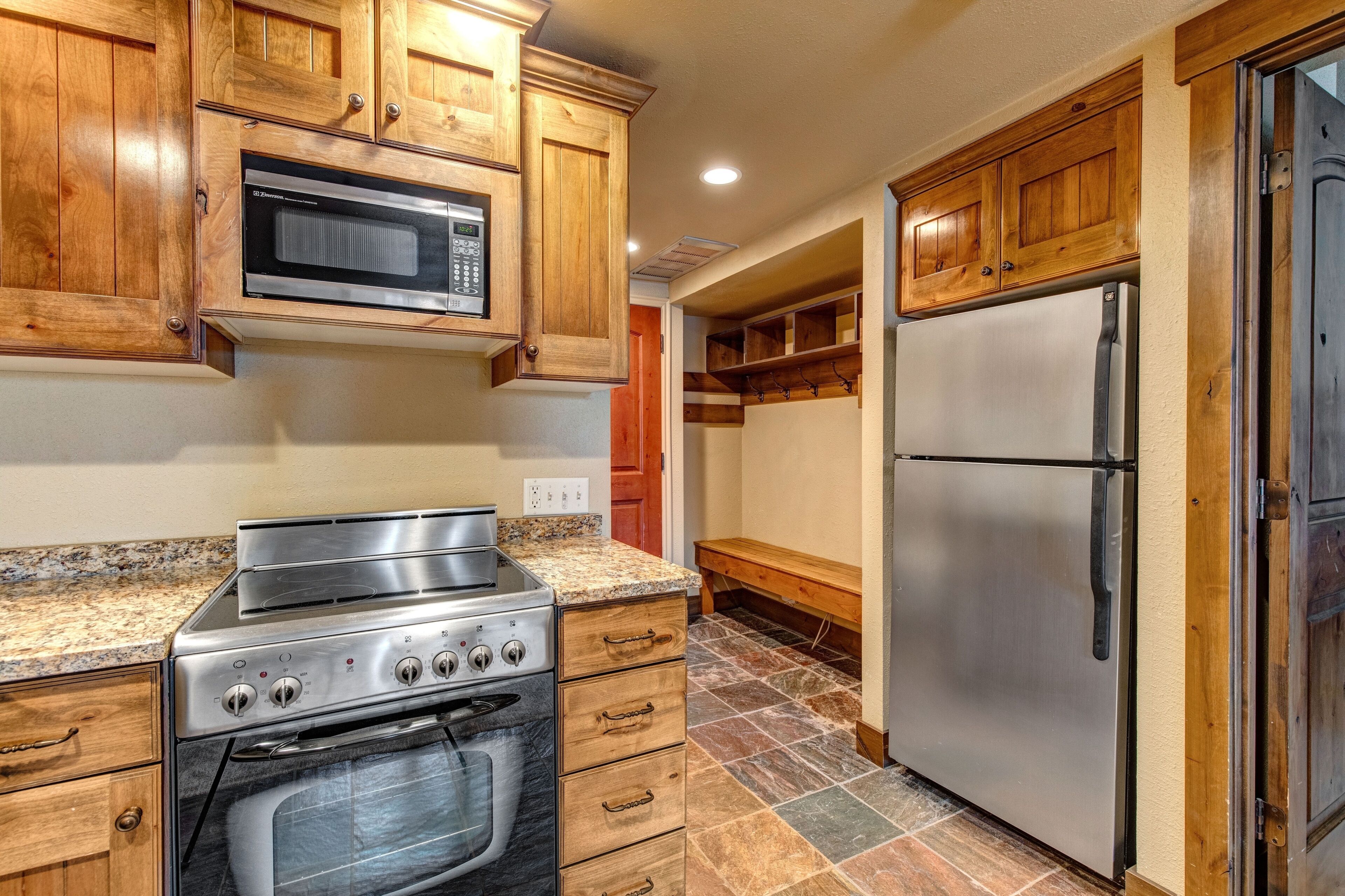 A kitchen with wooden cabinets, a stainless steel stove, a microwave, and a refrigerator.
