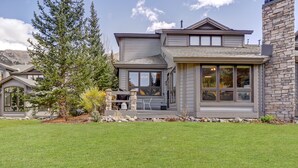 A modern two-story house with a stone chimney, large windows, and a well-maintained lawn. - Legends 11 5 Bedroom Townhouse (Copper Mountain)
