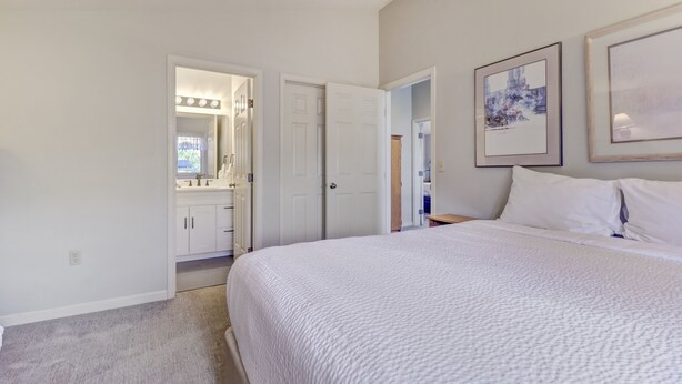 A bedroom with a large bed, a walk-in closet, and a bathroom with a mirror and vanity. - Legends 11 5 Bedroom Townhouse (Copper Mountain)