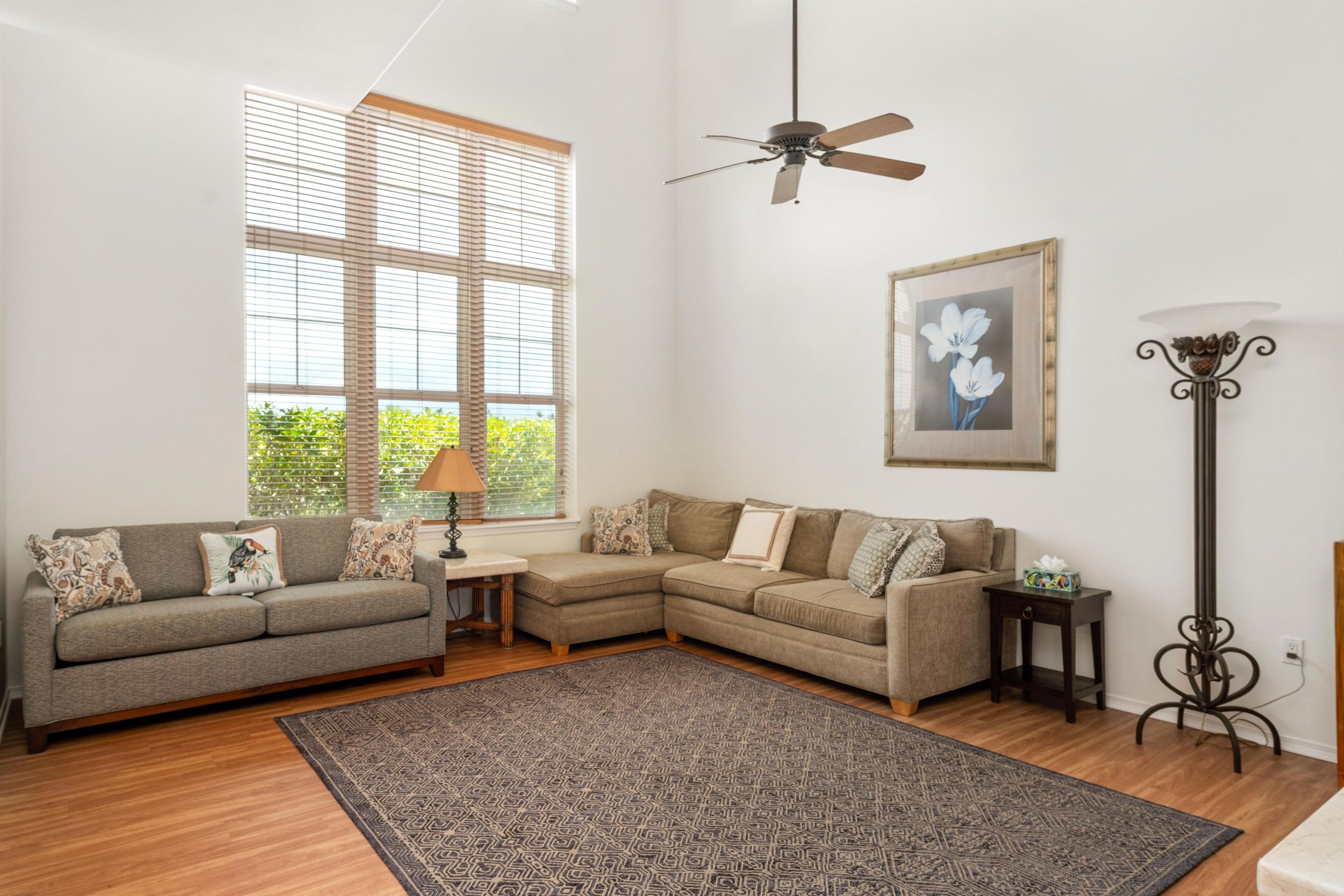 A living room with a sectional sofa, a small side table, a floor lamp, and a ceiling fan.