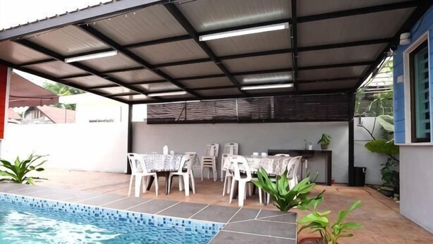 A covered outdoor area with a swimming pool, white chairs, and potted plants. - Voon Cottages@Pinjistation Private Pool 10pax (Ipoh)