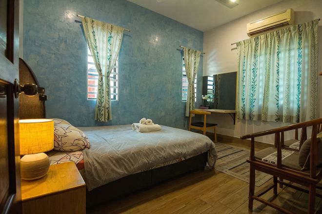 A bedroom with a bed, bedside table, lamp, and curtains.