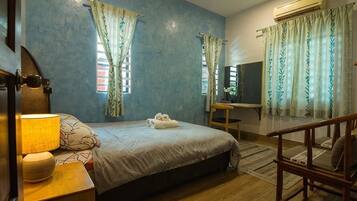 A bedroom with a bed, bedside table, lamp, and curtains.
