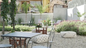 A patio area with outdoor seating, including a table and chairs, surrounded by gravel and potted plants. - PALAZZO RICARDI (Imperia)