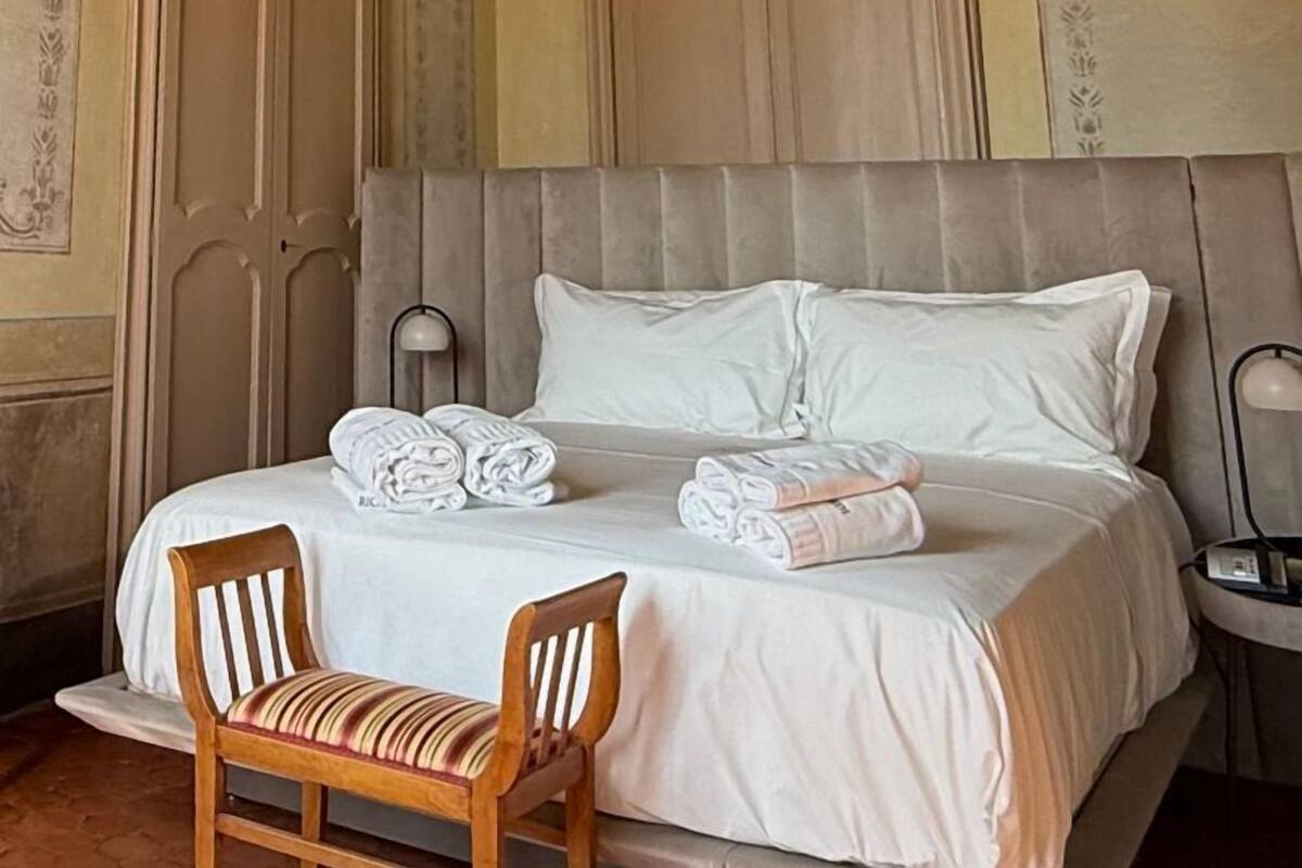 A hotel room with a large bed, a chandelier, and ornate ceiling decorations.