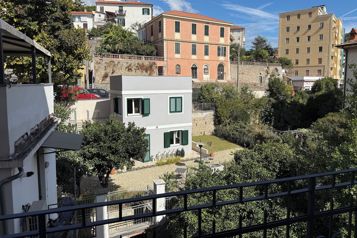 A residential area with buildings of various architectural styles, including a pink building with green shutters and a white building with a balcony.