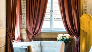 A room with a sofa, a window with curtains, and a vase with flowers. - PALAZZO RICARDI (Imperia)