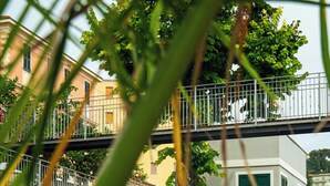 A swimming pool with a tiled deck, surrounded by greenery and a building with a balcony. - PALAZZO RICARDI (Imperia)