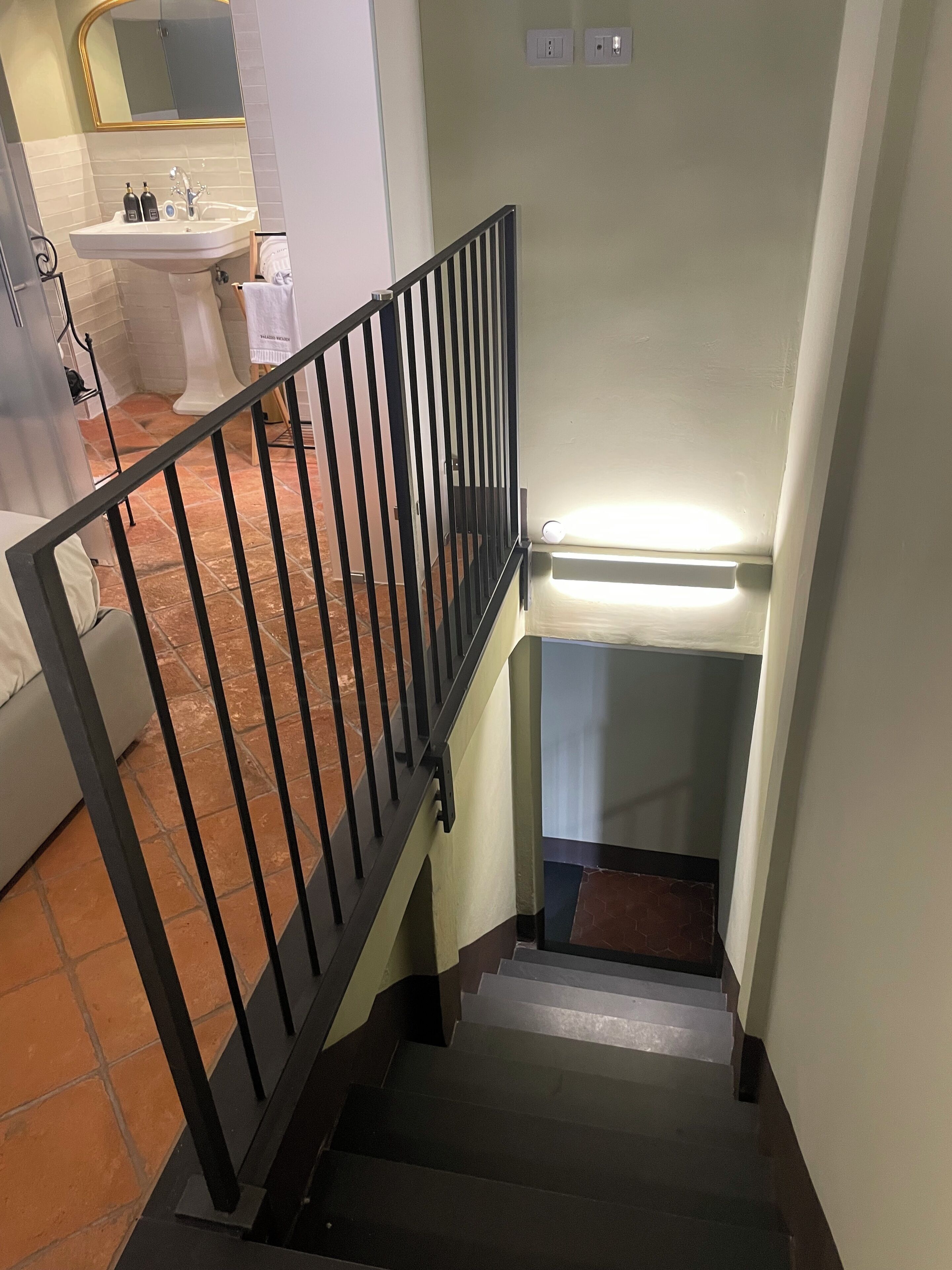 Eine Treppe mit schwarzer Metallreling, die zu einer Zwischenebene führt.