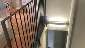 Eine Treppe mit schwarzer Metallreling, die zu einer Zwischenebene führt.