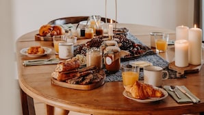 A breakfast setting with bread, pastries, and beverages on a wooden table. - Domaine Des Pousses (Droue-sur-Drouette)