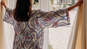 A person standing by a window with curtains, looking outside. - Domaine Des Pousses (Droue-sur-Drouette)
