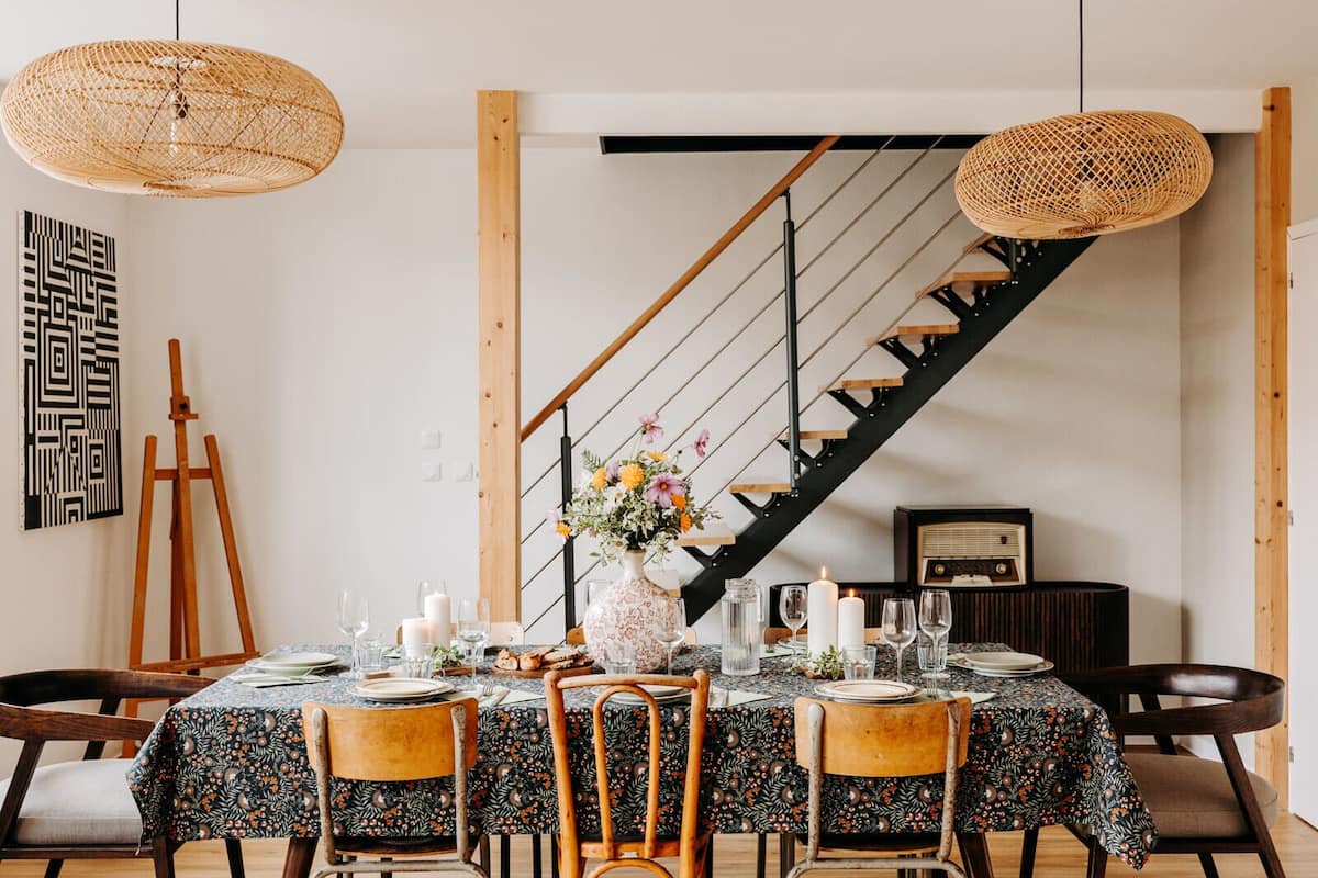Un coin repas avec une table dressée pour quatre personnes, un escalier et une œuvre d’art accrochée au mur.