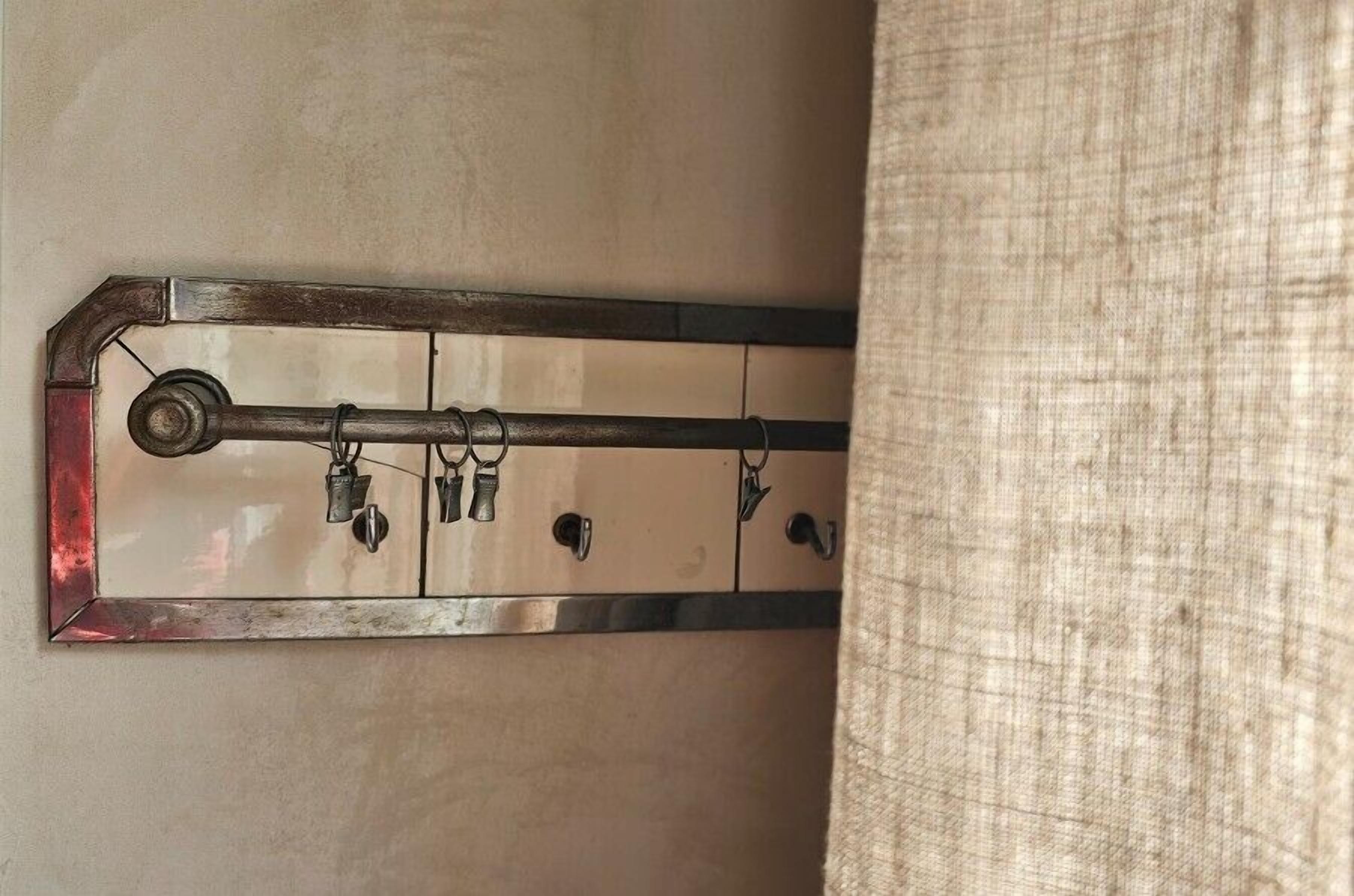 A metal rack with hooks, likely for hanging coats or bags, mounted on a wall.