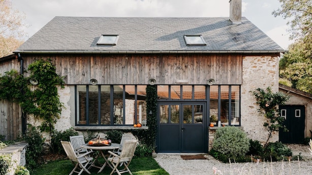 A rustic house with a stone facade, large windows, and a black door. - Domaine Des Pousses (Droue-sur-Drouette)