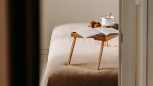 A bedroom with a bed, a wooden stool, a cup, and a bowl on a bedside table. - Domaine Des Pousses (Droue-sur-Drouette)