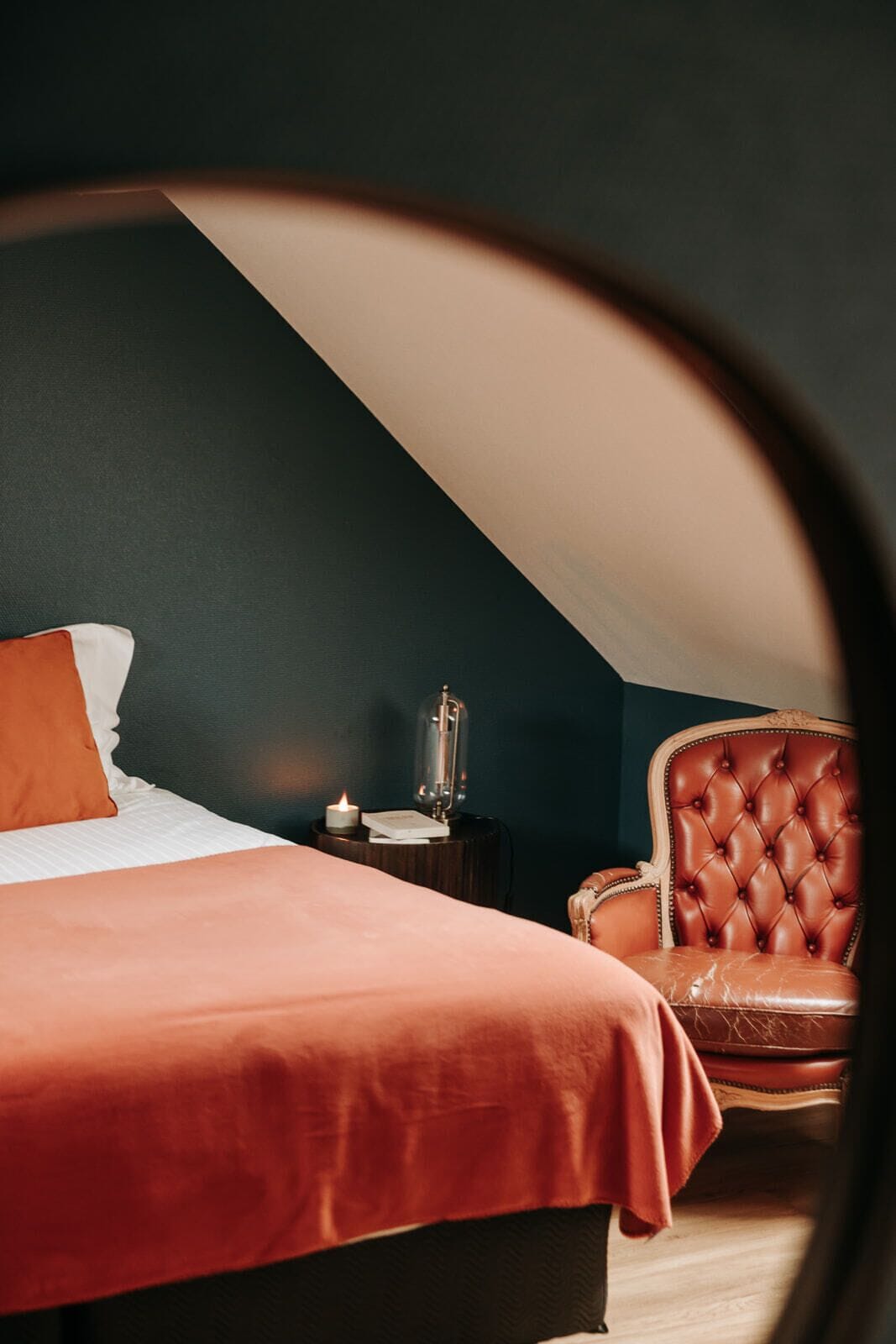 A bedroom with a bed, a chair, a nightstand, and a lamp.