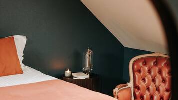 A bedroom with a bed, a chair, a nightstand, and a lamp.