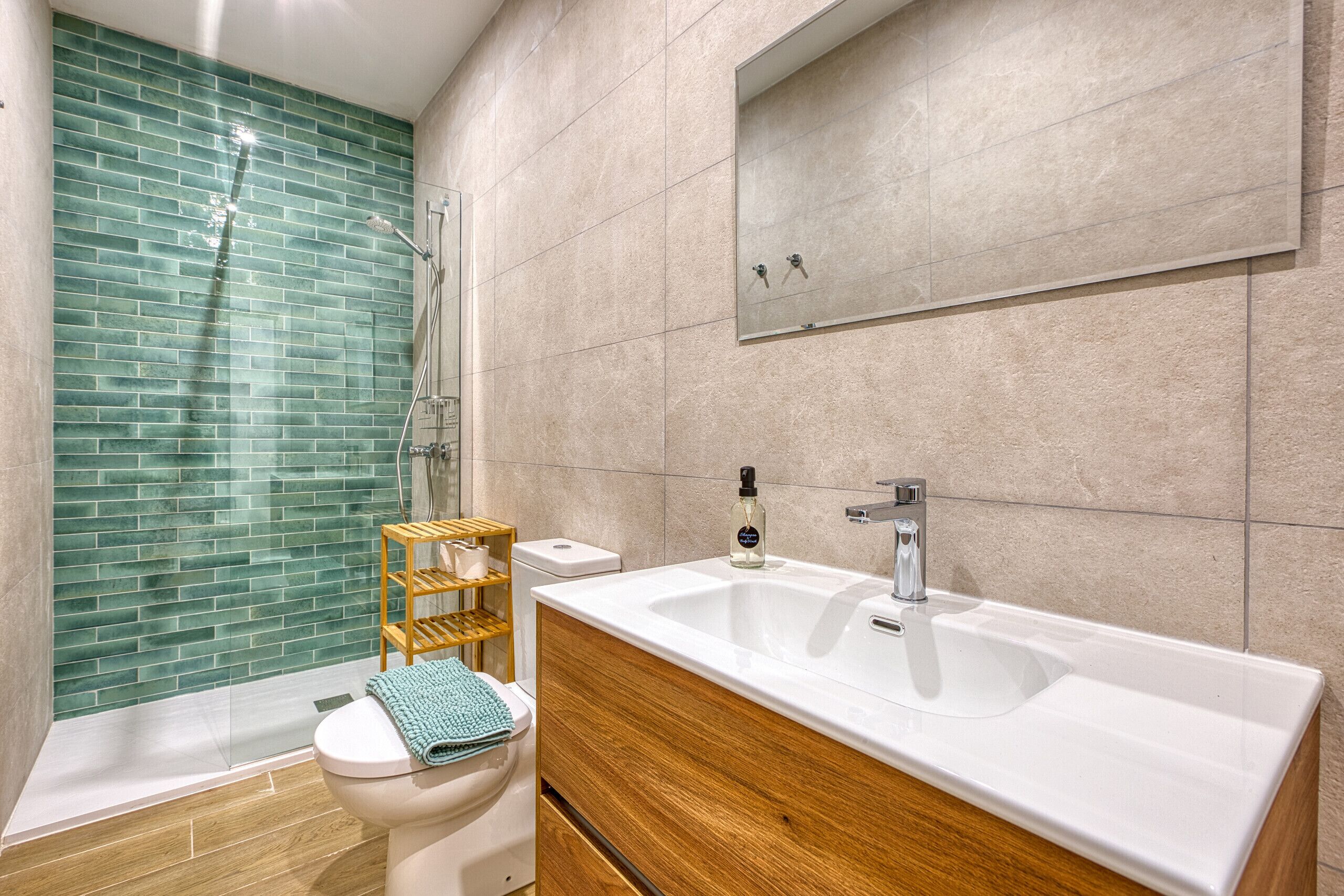 A modern bathroom with a glass shower enclosure, a wooden vanity, and a large sink.