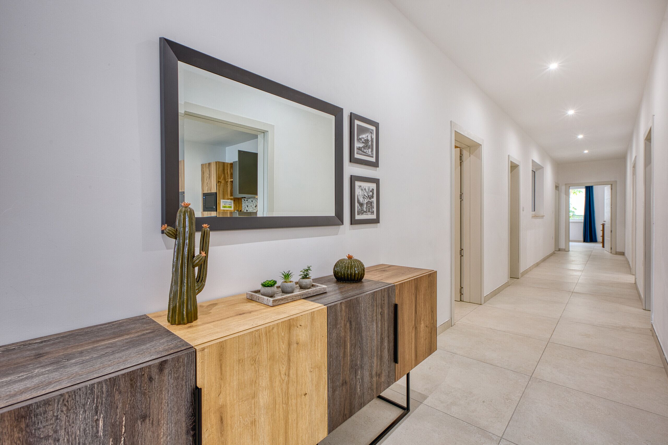 Un couloir avec une console en bois, un grand miroir et des tableaux encadrés accrochés au mur.
