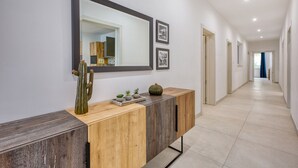 A hallway with a wooden console table, a large mirror, and framed pictures on the wall. - Spacious & Cozy 4-Bedroom in Sliema JELL1-2 (Sliema)